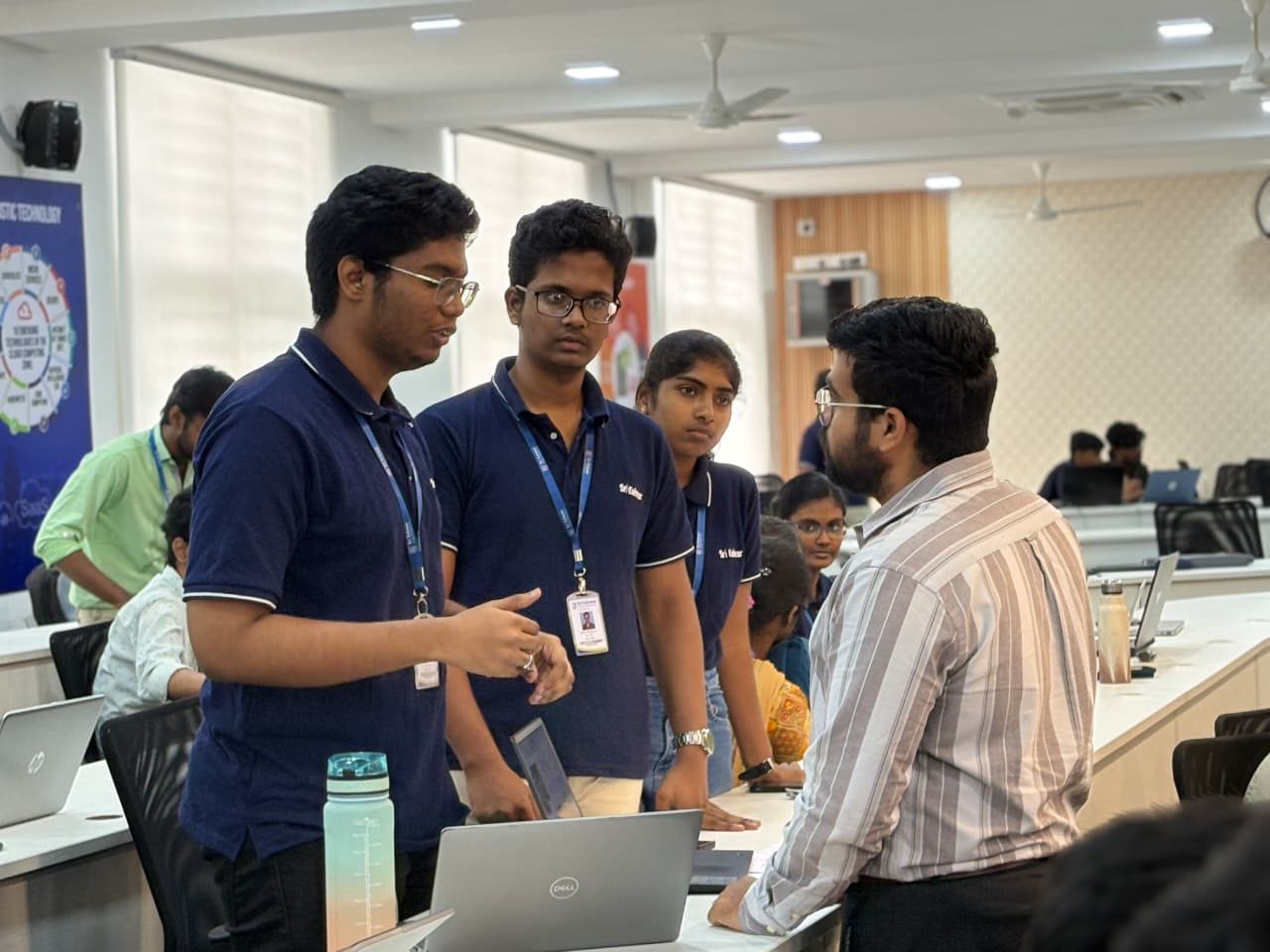 Three students in blue polo shirts presenting the multilingual LLM finance assistant to a judge at the GenAI Hackathon.