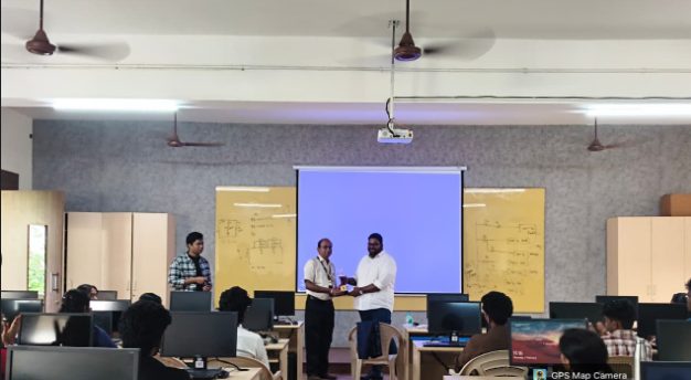 Student coordinator receiving a certificate shield in front of a classroom during the GitHub Ignite open-source workshop.